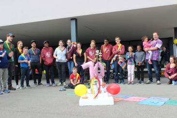 Eine Gruppe Kinder und Jugendliche steht um eine grosse 70Jahr Torte aus Styropor geschmückt mit Ballonen